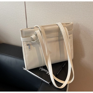 Detail of off-white retro tote bag with multi-pocket design on a leather seat