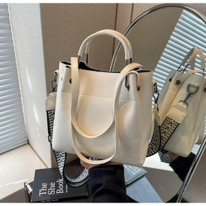 Détail du sac seau en cuir blanc avec une large bandoulière tissée à motifs géométriques