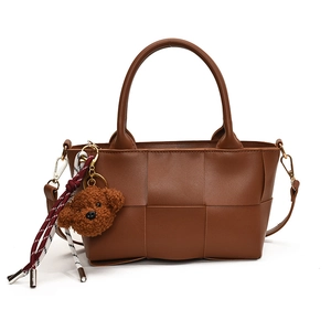 Sac à main en cuir tressé marron avec bandoulière et pendentif chien mignon sur fond blanc