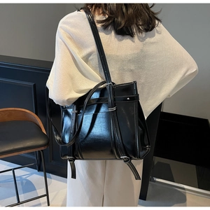 Detail view of the glossy black faux leather tote bag with silver metal buckles