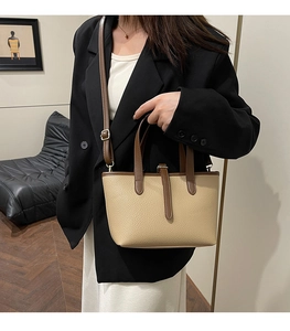 Close-up of contrast faux leather bucket bag showing beige texture and brown trim detail