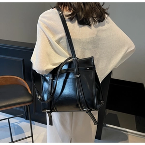 Close-up of a large black glossy leather tote bag with stylish metallic buckle details