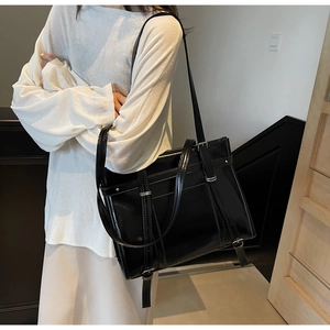 Glossy black PU leather tote bag with silver buckles and studs shown on a model