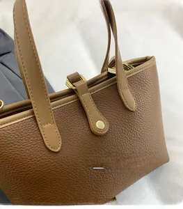Close-up of brown lychee texture leather bucket bag with gold hardware and stitching