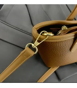 Close-up of brown lychee leather bucket bag with gold hardware and removable strap