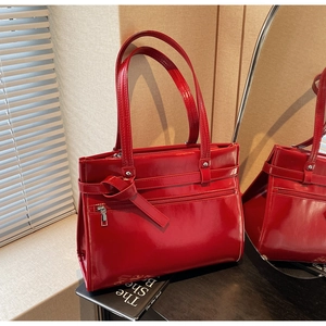 Detail of red patent leather tote bag with knot decor and shiny high-gloss finish