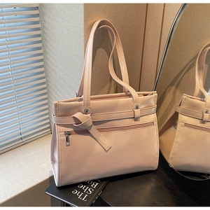 Detail of light pink tote bag with front zipper pocket and stylish knotted strap accents