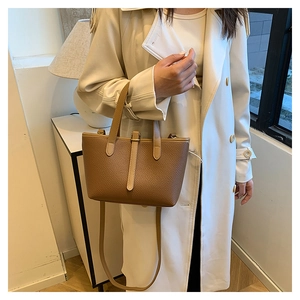Brown lychee grain leather bucket bag shown with trench coat for a stylish fall look