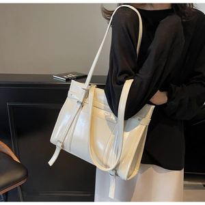 Chic white patent leather shoulder bag with buckle detail shown in a modern interior
