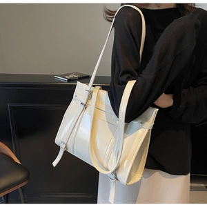 Close-up of cream white glossy tote bag with silver buckle and sleek leather texture