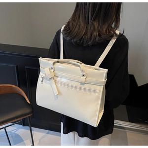 Detail of cream faux leather backpack featuring knot buckle straps and metal zippers