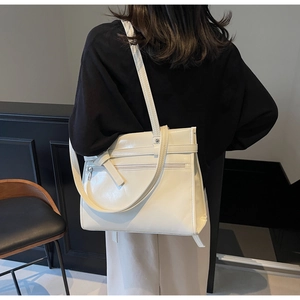 Close-up of white glossy tote bag with stylish belt buckle and front zipper pocket detail