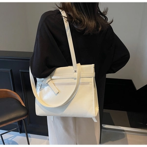 Detailed back view of a model wearing a cream oversized faux leather tote shoulder bag