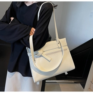 Detail of minimalist cream leather tote bag with functional zipper and adjustable shoulder strap