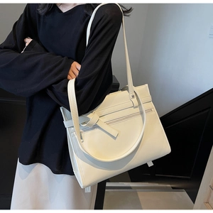 Detail of a large cream white PU leather tote bag with front zipper and dual shoulder straps