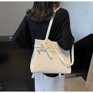 Detail of cream large tote bag featuring long straps and decorative leather knot