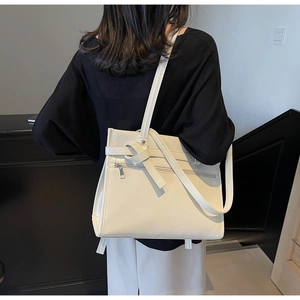 Detail of cream rectangular PU leather tote bag with decorative knot and zipper pocket