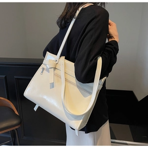 Close-up of cream white faux leather tote bag with elegant bow detail on shoulder strap