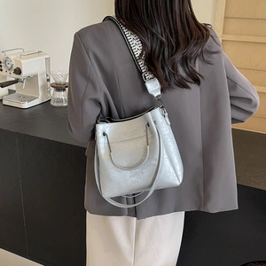 Sac cabas argenté rétro avec bandoulière géométrique porté par un mannequin au café