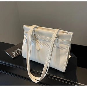 Detail of cream patent leather tote with metal buckle and functional front zipper