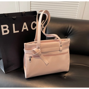 Close-up of light pink tote bag with decorative knot detail and front zipper pocket