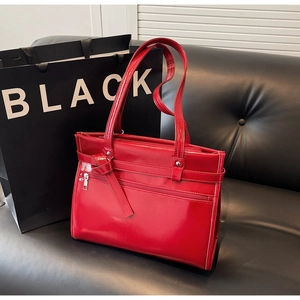 Close-up of bright red patent leather handbag with glossy texture and zipper detail