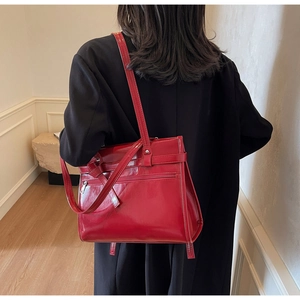 Detailed view of the red glossy leather tote bag showing zippers and vintage texture