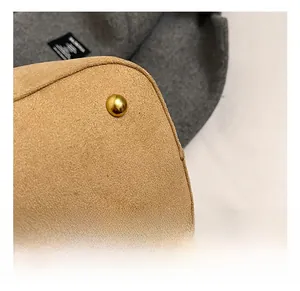Detail shot of golden metal base studs on a vintage camel suede bucket handbag