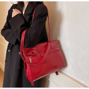 Macro shot of red patent leather shoulder bag with decorative knot and zipper detail