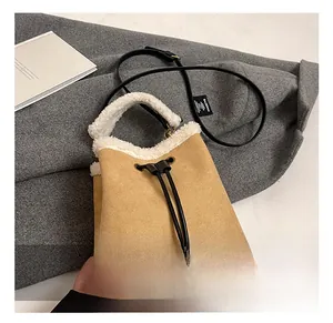 Detail of camel suede bucket bag with white faux shearling trim and black drawstrings