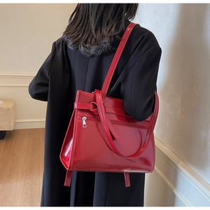 Macro view of bright red glossy patent leather tote bag with stylish knotted strap detail
