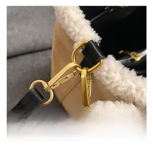 Detailed view of the gold metal hook and black leather strap on a brown suede bucket bag