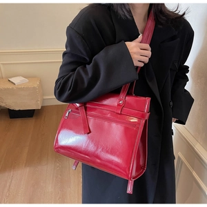 Detail of red glossy tote bag featuring a front zipper pocket worn with a black blazer