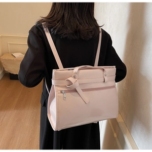 Close-up of a pink structured faux leather backpack worn on model's back for commute style