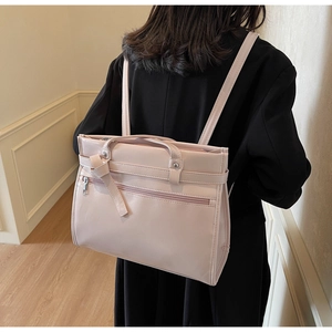 Detail showing back view of pink leather multi-way handbag worn with a black coat
