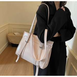 Detail of glossy leather tote bag with silver metal buckles and decorative straps