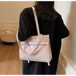 Detail of light pink patent leather tote bag with exterior zipper and ribbon accent
