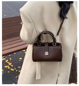 Deep brown lychee leather crossbody bag with silver buckle worn by model in a park