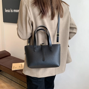 Black lychee leather bucket tote bag with gold buckle detail and adjustable strap