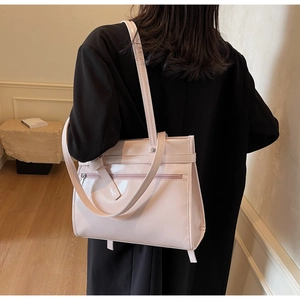 Back view of light pink glossy tote bag with metal zipper on a black coat model