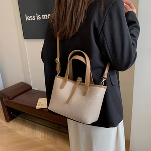 Chic beige lychee grain bucket bag with brown handles, styled on a professional model