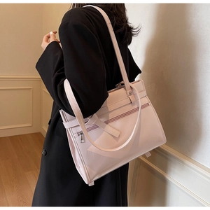 Detail view of pink PU leather tote bag with side zippers worn with a black blazer