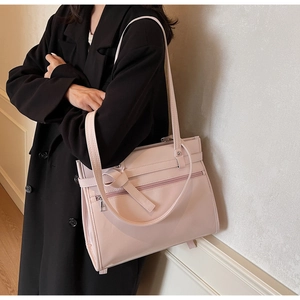 Detail of pink PU leather tote bag featuring a front zipper pocket and knotted shoulder strap