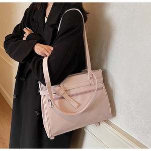 Detail of light pink tote bag featuring front zip pocket and decorative knot detail