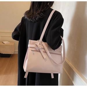Side view of a light pink tote bag with stylish knot detail and decorative strap on model