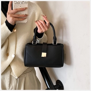 Close-up of black lychee texture leather bag featuring a gold square metal buckle