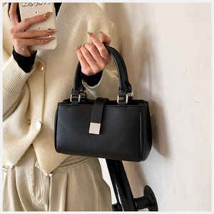 Close-up of black pebble grain leather handbag with elegant silver hardware and top handle