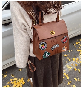 Dettaglio ravvicinato dello zaino vintage in pelle marrone con stemmi in stile college