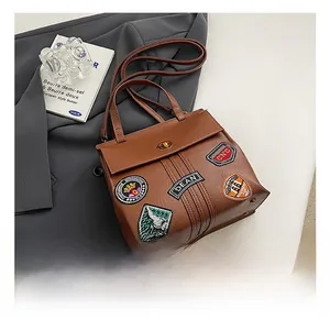 Dettaglio della borsa tote marrone vintage con toppe ricamate retro e chiusura in oro