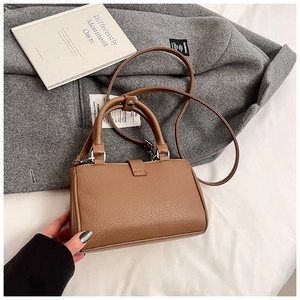 Detail view of a brown pebbled leather crossbody bag with silver hardware on a wool coat